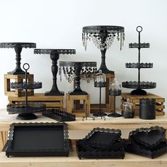 a table topped with lots of black vases and candlesticks on top of wooden boxes