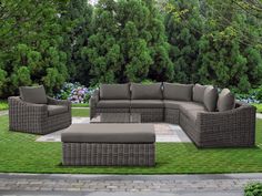 an outdoor patio furniture set with grey cushions on the grass and trees in the background