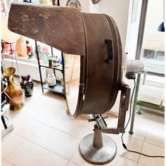 an old fashioned hair dryer sitting on top of a metal stand in a room