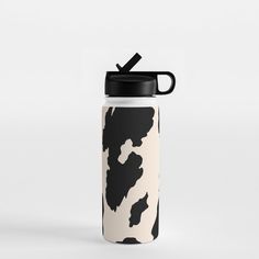 a black and white cow print water bottle with a straw in it's mouth