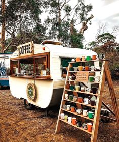 an old camper parked on the side of a dirt road next to a tree