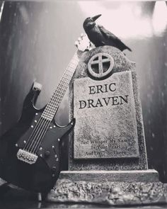 a black and white photo of an electric guitar next to a grave