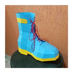 a pair of blue and yellow boots sitting on top of a green stool next to a wall