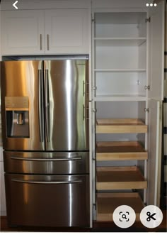 a stainless steel refrigerator in a white kitchen with steps leading up to the bottom cabinet