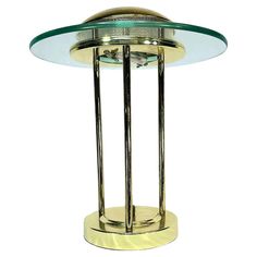 a glass and brass table with a metal base