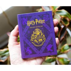 a person holding up a harry potter sticky note set in front of a planter