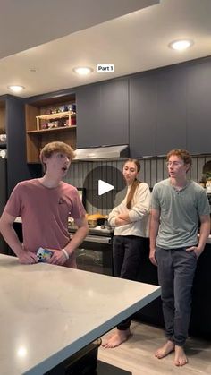 three people are standing in the kitchen looking at something