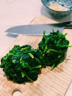 a cutting board topped with greens next to a knife