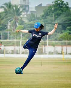 a woman kicking a soccer ball on top of a field