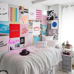 a bedroom with white bedding and lots of posters on the wall