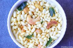 a white bowl filled with corn and nuts on top of a blue tablecloth next to a spoon