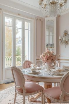 an elegant dining room with pink chairs and chandelier