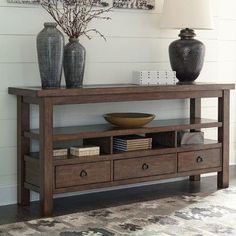 a living room with a table and vases on top of the shelf next to it