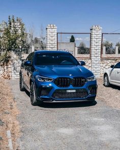 two bmw cars parked in front of a brick wall