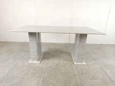 a white table sitting on top of a hard wood floor next to a white wall