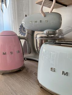 two pastel colored toasters sitting on top of a wooden table