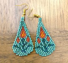 a pair of beaded earrings sitting on top of a wooden table