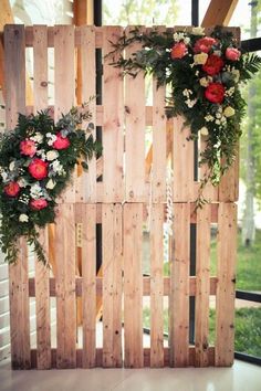 some flowers are hanging on a wooden fence with greenery and roses in the middle