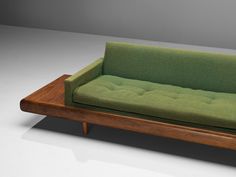 a green couch sitting on top of a wooden table