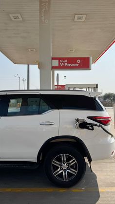 a white suv parked in front of a gas station