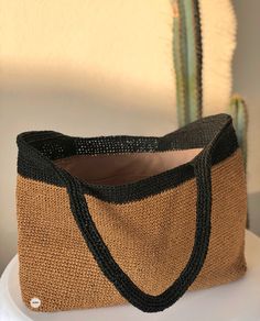 a brown and black bag sitting on top of a white plate next to a cactus