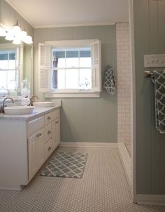 a bathroom with two sinks and a large window in the corner on the far wall