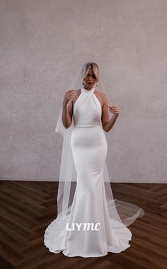 a woman wearing a white wedding dress with a veil on her head, standing in front of a wall