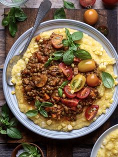 a white plate topped with polenta covered in meat and veggies