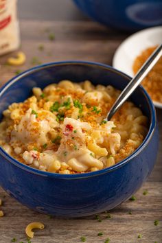 a blue bowl filled with macaroni and cheese on top of a wooden table