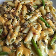 pasta with mushrooms, asparagus and cheese on a white plate in a creamy sauce