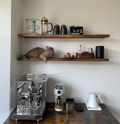 there is a coffee maker on the shelf next to two shelves with cups and an espresso machine