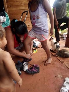 three children are playing with shoes on the ground