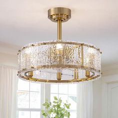 a chandelier hanging from the ceiling in a living room with white walls and windows