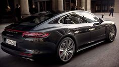 the rear end of a black porsche panamer parked in front of a building