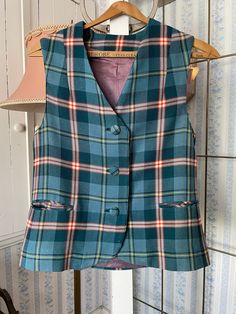 This beautiful wool blend vest was made by Bernard Casuals in Vancouver, in green, blue, red, yellow, beige and black plaid. It has the original cloth covered buttons in the front, two front pockets (that haven't been unstitched yet), and it is fully lined. Marked size 10. The measurements, taken with the vest lying flat, are: shoulder to shoulder, 14 inches; armpit to armpit, 17 1/2 inches; length, 21 inches in front and 22 1/2 inches in back; bottom edge, 18 1/2 inches. There is a small hole in the lining in the centre back; otherwise, the vest is in very good condition. See Vintage Pants & Skirts, item B547, for matching skirt/kilt! Plaid Vest For Fall, Plaid Sleeveless Vest For Fall, Fitted Plaid Vest For Winter, Fitted Plaid Sleeveless Vest, Vintage Green Vest For Fall, Green Vintage Vest For Fall, Fitted Sleeveless Plaid Vest, Plaid Sleeveless Vest For Work, Classic Plaid Vest For Fall