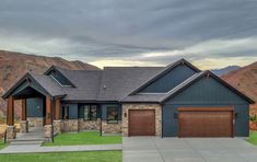 a large house with two garages and mountains in the background