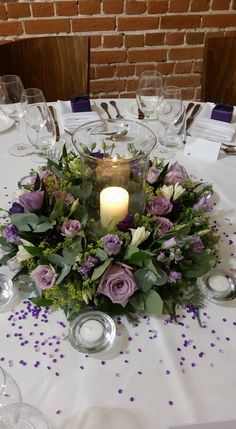 a centerpiece with flowers and candles on a table