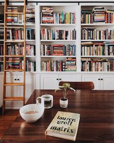 a book shelf filled with lots of books next to a bowl of cereal and a ladder