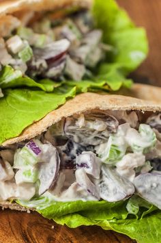 two pita sandwiches with lettuce and chicken salad on them sitting on a wooden table