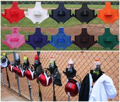 there are many different types of sports equipment hanging on the fence and behind them is a baseball field