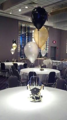 some balloons are hanging from the ceiling in a banquet hall with tables and chairs set up for an event