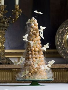 there is a cake that has been decorated with white butterflies on it and sits on top of a glass plate