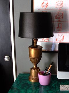 an image of a desk with a lamp on top of it and a computer in the background