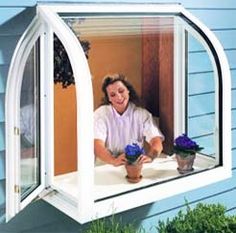 a woman sitting in a window with potted plants