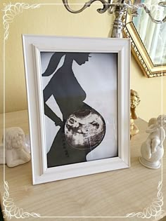 a white frame with an image of a woman holding a baby in her arms on top of a table