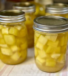 several jars filled with pickles sitting on top of a tablecloth covered table cloth