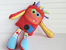 a red stuffed animal sitting on top of a white table next to a wooden wall