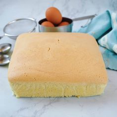 a square cake sitting on top of a counter next to measuring spoons and an egg