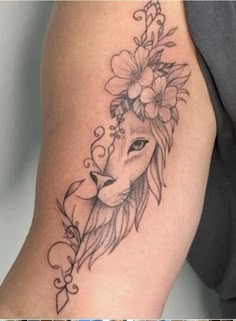 a woman's arm with a lion tattoo on it and flowers in her hair