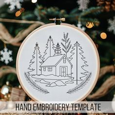 a hand embroidered christmas ornament with a house in the woods